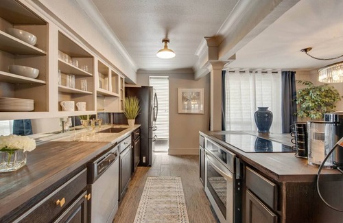 Lower Greenville Condo | Experience elevated comfort in this upscale 2-bedroom Dallas condo with pool views and exclusive access to an award-winning courtyard featuring a resort-style pool, hot tub, dry sauna, and lush lounge areas. Enjoy a 77″ smart TV, sleek leather sofa,