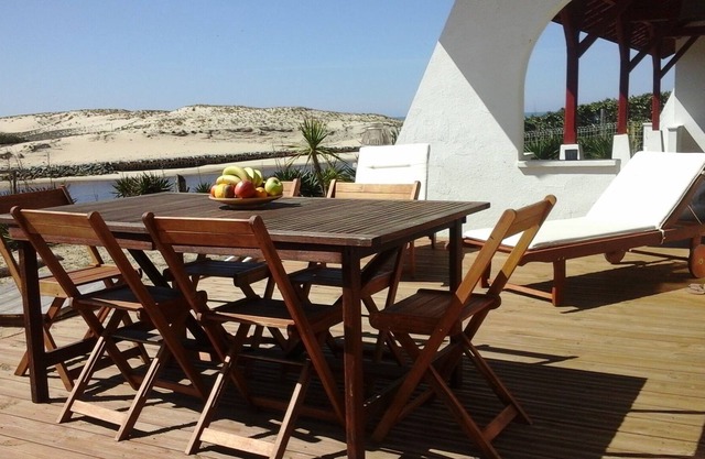 house with breathtaking view of river and sea, feet in the sand.